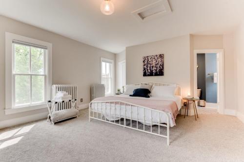 Dormitorio blanco con cama blanca y ventanas en The Guest House - Estate, en Excelsior