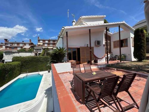 a patio with a table and chairs next to a pool at Casa familiar en la playa con piscina in Teià