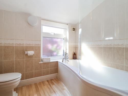 a bathroom with a tub and a toilet and a window at Green Gate Cottage in Southwold
