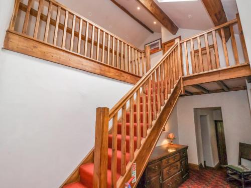 a wooden staircase in a house with a red chair at Bay Horse Farm in Skipton