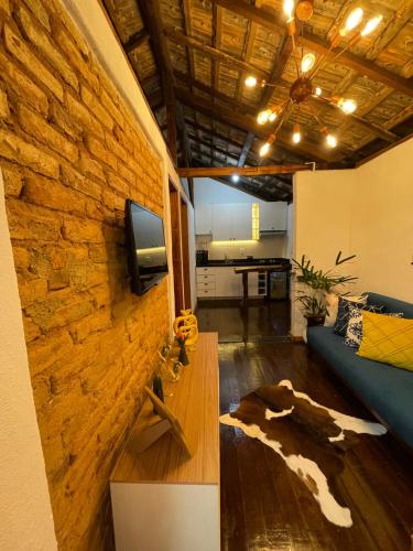 a living room with a couch and a tv on a brick wall at Chácara da Tuia in Estancia do Castello