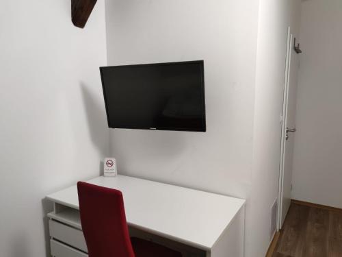 una scrivania bianca con sedia rossa e una TV a parete di Penzion Na Protivínské a Strakonice
