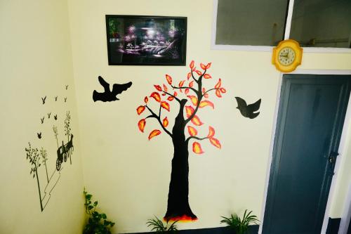 Namaskar Lodge and Homestay في غاواهاتي: شجرة و خفافيش على جدار مع ساعة