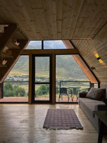 a living room with a couch and a large window at Gagma chalets in Stepantsminda