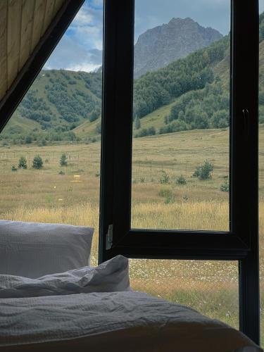 a bedroom with a view of a field from a window at Gagma chalets in Stepantsminda