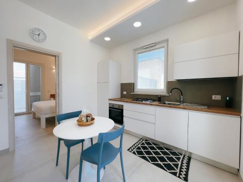 een keuken met een tafel, stoelen en een spoelbak bij La Casa sulla Spiaggia Torre San Giovanni in Torre San Giovanni Ugento