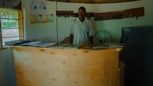 un hombre parado detrás de un mostrador de madera en una habitación en AFLII Guest house, en Mtwara
