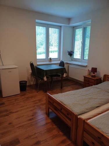 ŘíčkyにあるHostinec Klopotyのベッド2台、テーブル、窓が備わる客室です。