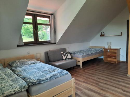 sypialnia z 2 łóżkami, krzesłem i oknem w obiekcie Ubytování U Bohouše w mieście Horní Radouň