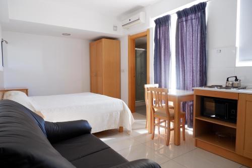 una camera con letto e una cucina con tavolo di Shamrock Apartments a San Pawl il-Baħar