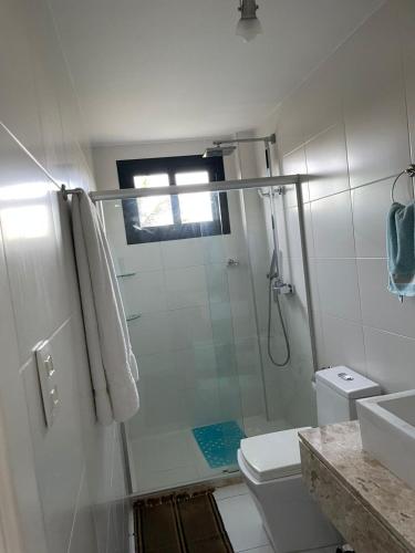 a white bathroom with a shower and a toilet at Paribahia in Praia do Forte