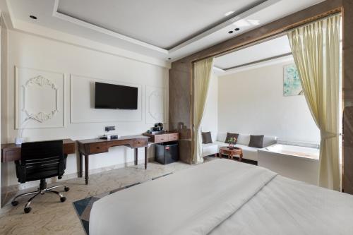 a bedroom with a bed and a desk with a computer at Hotel Caesars Palace in Bhopal