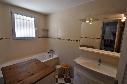 ein Badezimmer mit einer Badewanne, einem Waschbecken und einem Spiegel in der Unterkunft VAUJANYLOCATIONS - Roches Grandes 49 in Vaujany