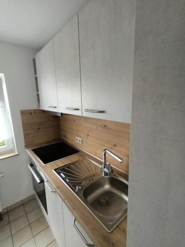 a small kitchen with a sink and white cabinets at Apartment Schwalbenweg - Günstige Langzeitvermietung in Gelnhausen