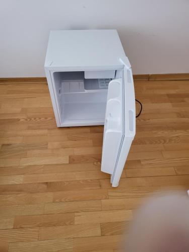 an open white refrigerator sitting on a wooden floor at Soba L&L Povljana in Povljana