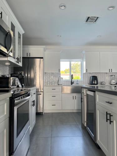 a kitchen with white cabinets and stainless steel appliances at House Of Art - Luxury Villa with Pool & Jacuzzi! in Tamiami