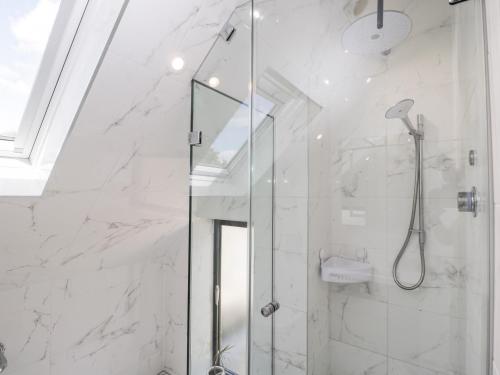 a bathroom with a shower with white marble walls at Suncroft in Cheltenham