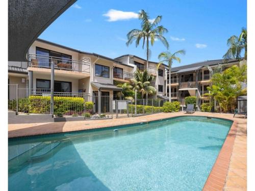 een zwembad voor een gebouw met palmbomen bij Beachfront Apartments in Port Macquarie