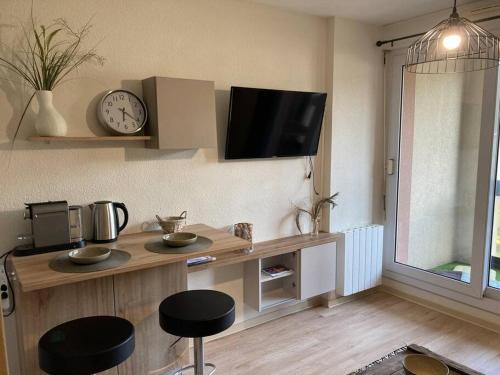 eine Küche mit einem Tisch mit zwei Hockern und einer Uhr in der Unterkunft Studio au cœur de chatelguyon in Châtel-Guyon