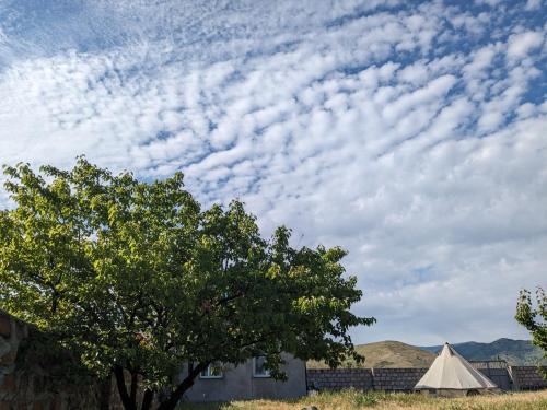 una tienda y un árbol y un cielo con nubes en Campy Mountain Campsite, en Tkhit