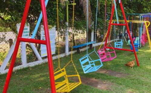a playground with colorful swings in the grass at Pousada Jovimar in Aparecida