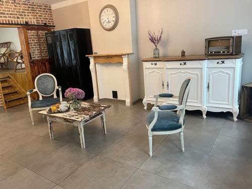 - un salon avec des chaises, une table et une horloge dans l'établissement La maison de Solange, à Esquelbecq