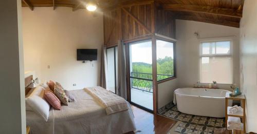 ein Schlafzimmer mit einem Bett, einer Badewanne und einem TV in der Unterkunft Villas Flakis, Luna in Monteverde Costa Rica