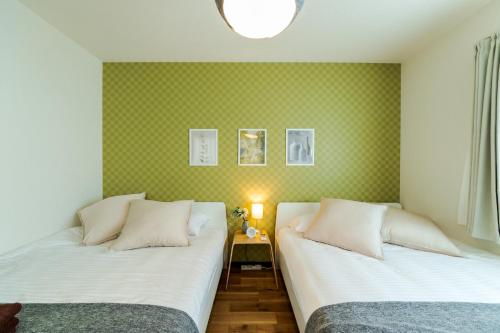 2 łóżka w pokoju z zieloną tapetą w obiekcie Wakamiya detached house - Vacation STAY 35575v w Tokio