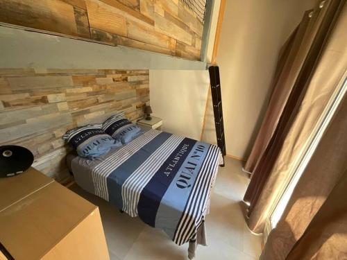 1 dormitorio con 1 cama y pared de madera en Charmant T2 3 Lits 4 personnes et 1enfant 55m2 parking et terrasse, en Saint-Sever
