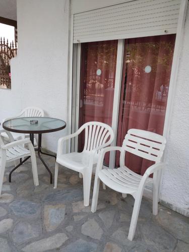 three white chairs and a table on a patio at PELEKAN rooms and apartments athina 11 in Pefkochori