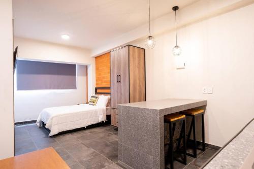 1 dormitorio con 1 cama y 1 mesa en una habitación en Ihost Chapultepec @Serra, en Guadalajara