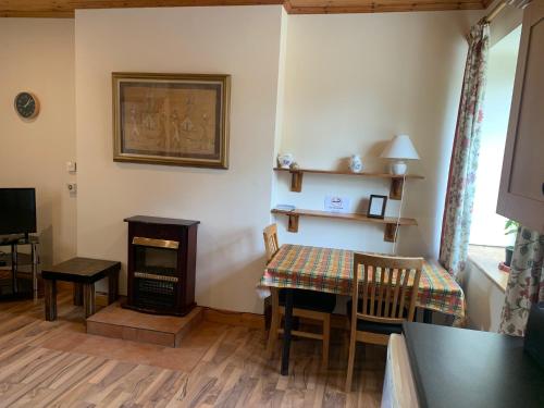uma sala de jantar com uma mesa e um fogão em Castlehamilton Mill Cottage em Killashandra