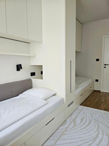 Schlafzimmer mit weißen Schränken und einem Bett mit Spiegel in der Unterkunft ADAV Luxus Apartment in Visoko