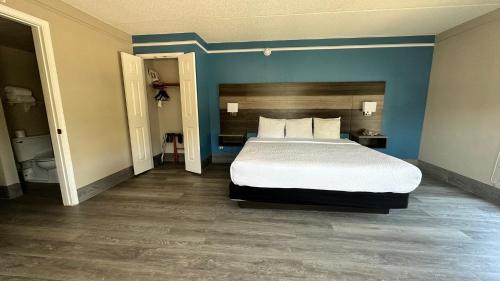 a bedroom with a bed and a blue wall at Days Inn by Wyndham San Diego Vista in Vista