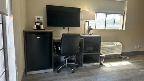 a room with a computer desk with a monitor and a chair at Days Inn by Wyndham San Diego Vista in Vista