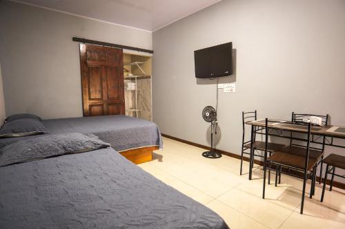 a bedroom with two beds and a desk and a television at Apartamento Quepoa in Quepos