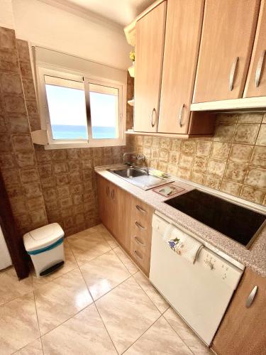 a kitchen with wooden cabinets and a sink and a window at Apartamento Luz del Mar in Torrox Costa