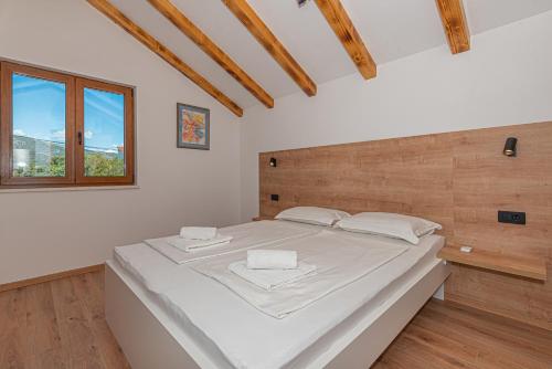 una camera da letto con un grande letto bianco con testiera in legno di Casa del sol a Južni Škugori