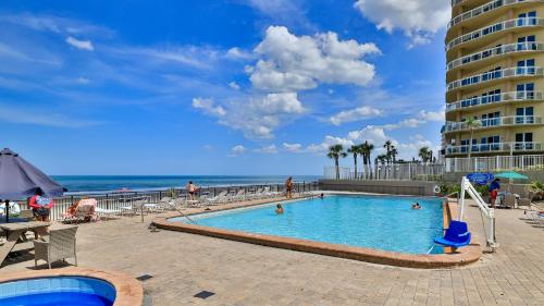 a swimming pool next to a beach with a building at Oceanside Inn in Daytona Beach