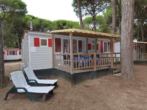 リド・ディ・スピーナにあるDetached mobile home with terrace near the sea on the Adriatic coastの小さな家 ポーチと椅子2脚付