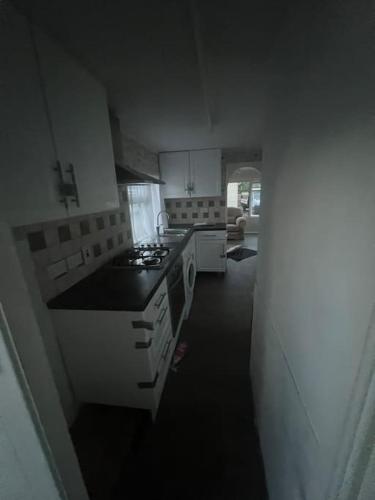 a kitchen with white cabinets and a stove top oven at Mobile home for rent in Hascombe