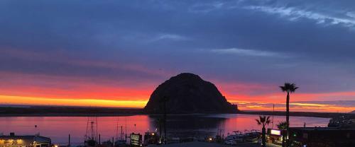 a mountain in a body of water at sunset at Bayfront Inn in Morro Bay