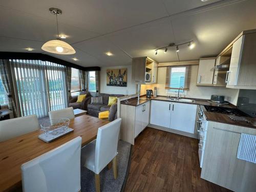 a kitchen and living room with a table and a kitchen and a dining room at 8 berth pet friendly caravan Lyons Robin Hood in Meliden