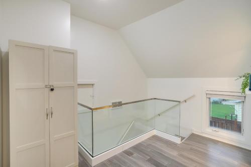 a glass staircase in a white room with a window at South Haven Oasis - Private Hot Tub, Pool and Grill! in South Haven