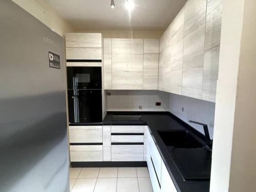 a kitchen with white cabinets and a black refrigerator at Intero Appartamento a Pescara in Pescara