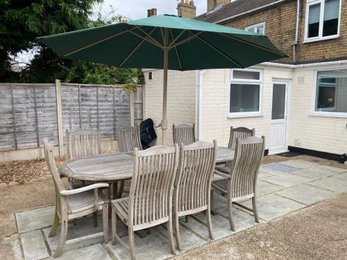 a wooden table with chairs and a green umbrella at Lincoln House in Lincoln