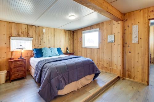 a bedroom with wooden walls and a bed with blue pillows at Bandon Home with Patio, Steps to South Jetty Park in Bandon