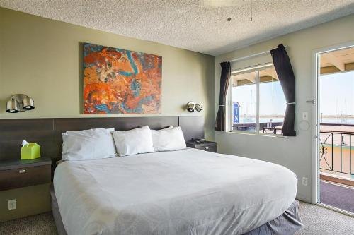 a bedroom with a large white bed and a window at Bayfront Inn in Morro Bay