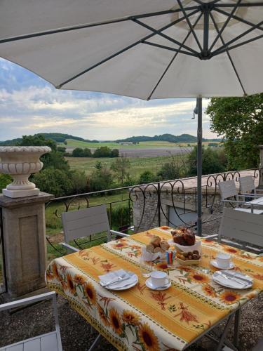 uma mesa com um guarda-chuva e um prato de comida em LA MAISON FORTE em Montaut