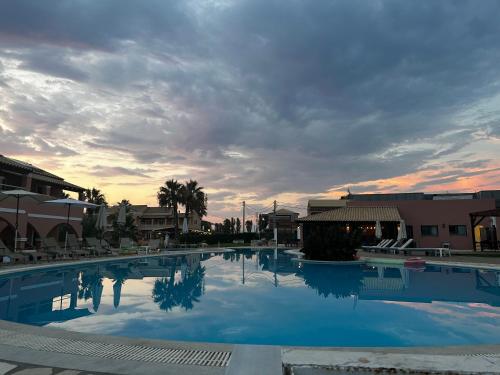 a large swimming pool with a sunset in the background at Perland Vacation in Sidari
